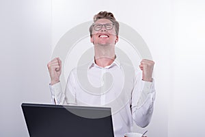 Young business man cheering his success while working on laptop