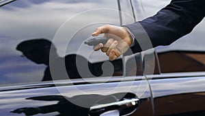 Young business man closing his car door with remote control key, close up