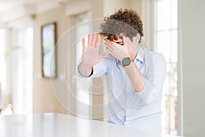 Young business man with curly read head covering eyes with hands and doing stop gesture with sad and fear expression