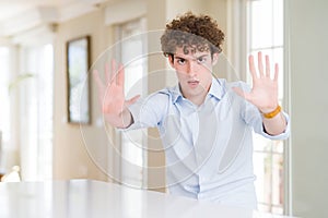 Young business man with curly read head doing stop gesture with hands palms, angry and frustration expression