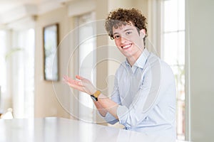 Young business man with curly read head pointing aside with hands open palms showing copy space, presenting advertisement smiling