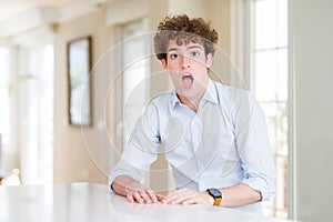 Young business man with curly read head In shock face, looking skeptical and sarcastic, surprised with open mouth