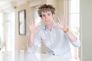 Young business man with curly read head showing and pointing up with fingers number ten while smiling confident and happy