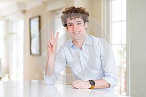 Young business man with curly read head showing and pointing up with fingers number two while smiling confident and happy
