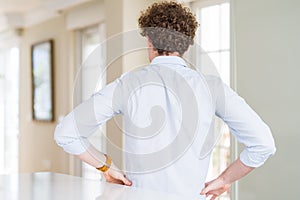 Young business man with curly read head standing backwards looking away with arms on body