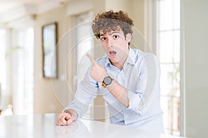 Young business man with curly read head Surprised pointing with finger to the side, open mouth amazed expression