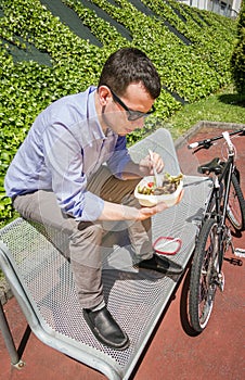 Young business man eating at lunch break outdoors