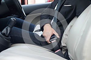 Young business man fastening seat belt in the car, Closeup hand male driver fastens seat belt