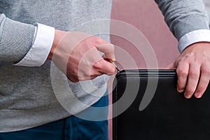 Young business man hand pulling a zipper to close a black leather laptop computer case. Working at the office