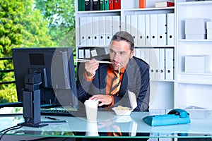 Young business man at his desk is eating