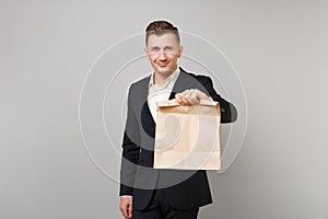 Young business man holding brown clear empty blank craft paper bag for takeaway mock up isolated on grey background