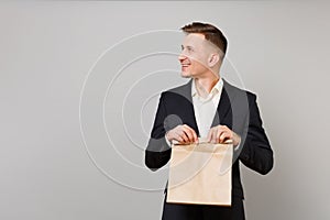 Young business man holding brown clear empty blank craft paper bag for takeaway mock up isolated on grey background