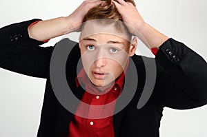 Young business man holding his head frowning with worry looking up.