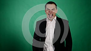 Young business man laughing diabolically on green background