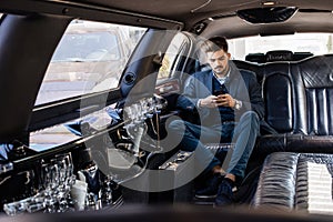 Young business man in limo typing on smart phone