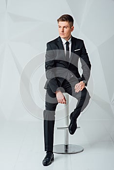 Young business man in modern suit sitting on chair