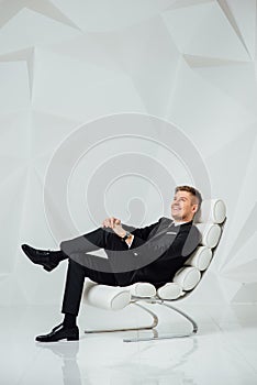 Young business man in modern suit sitting on chair