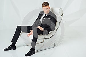 Young business man in modern suit sitting on chair