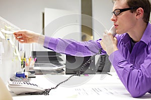 young business man on phone reading note in office