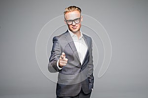 Young business man in glasses pointing and looking at the camera. on a gray background