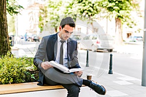 Young Business Man Reading Book While Drinks Coffee Outdoor