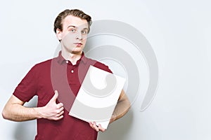 Young business man in red polo shirt holding blank A4 signboard paper showing thumb up . Business background with copy space