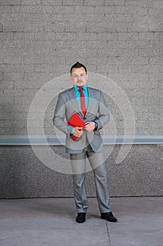 young business man with a red tie with a tablet on a gray background