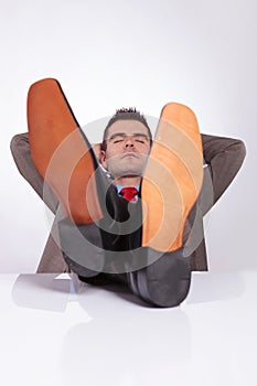 Young business man sleeps at office with feet on desk