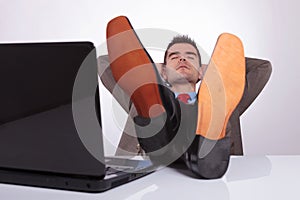 Young business man sleeps at work with feet on desk