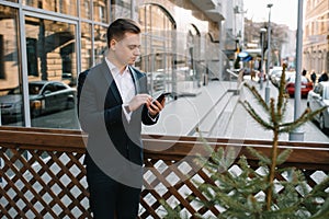 Young business man with a smartphone near of modern building