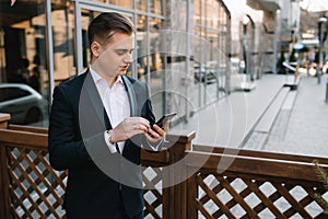 Young business man with a smartphone near of modern building.