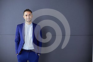 Young business man standing isolated on grey background