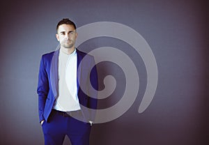 Young business man standing isolated on grey background