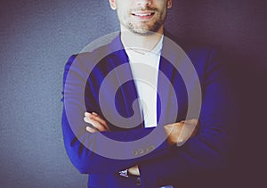 Young business man standing isolated on grey background