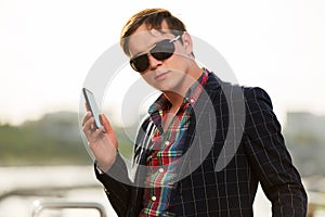 Young business man in sunglasses with a mobile phone