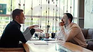 Young business man is talking with client at the table in the interior of cafe