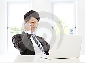 Young business man talking happily by smart phone in office