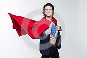 Young business man tearing apart his shirt revealing superhero suit, isolated on white background