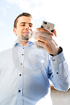 Young business man using cellphone laughing and typing message