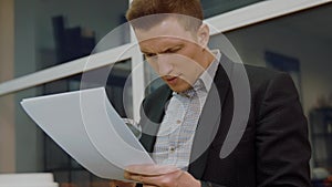 Young business man using magnifying glass for reading financial documents