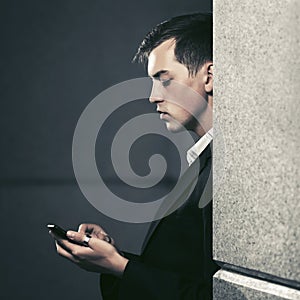 Young business man using smart phone in city street