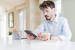 Young business man using touchpad tablet scared in shock with a surprise face, afraid and excited with fear expression