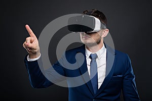 Young business man with VR glasses pointing at copyspace