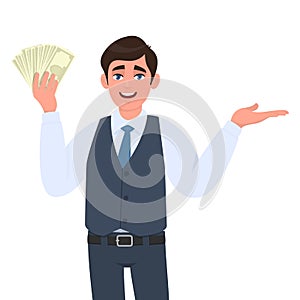 Young business man in waistcoat showing cash, money or currency notes and presenting hand to copy space. Person holding banknotes.