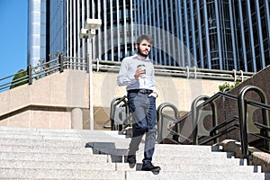 Young business man walking down stairs with a coffee cup in his hand