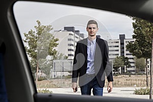 Young business man walking towards car