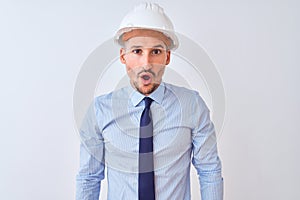 Young business man wearing contractor safety helmet over isolated background afraid and shocked with surprise expression, fear and