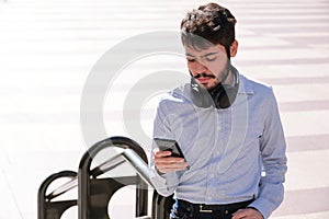 Young business man wearing headphones and using his smartphone