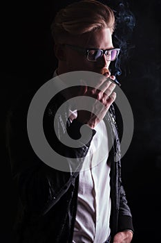 young business man wearing a leather jacket enjoying his cigarette.