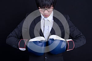 Young business man wearing suit with boxing gloves